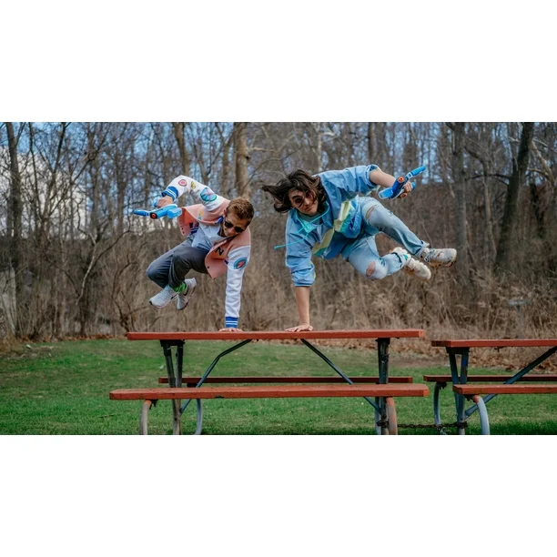 Dynamic shot of two people leaping off a picnic table, armed with blue Gelbee blasters, ready for an intense water bead battle outdoors. Captures the excitement of Gelbee action.